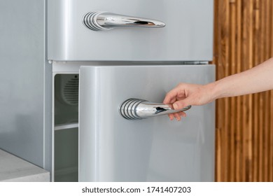 Cropped View Of Woman Hand Open Fridge Door, Standing In Contemporary Kitchen With Modern Interior. Housewife Using New Refrigerator In Dining Room