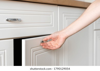 Cropped View Of Woman Hand Open Door At Cupboard Furniture Standing On Modern Kitchen At Home With White Interior