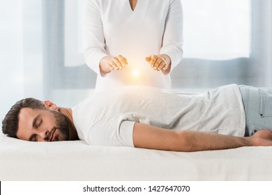 cropped view of woman healing man while putting hands above body