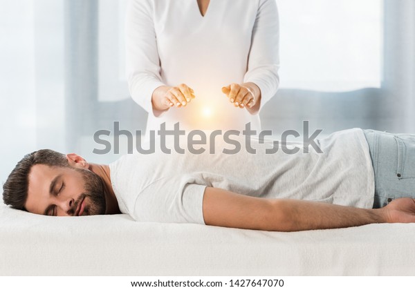 cropped view of woman healing man while putting\
hands above body