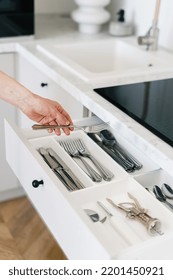 Cropped View Of Woman Hold Metal Fork In Hand, Standing On Kitchen Near White Open Cutlery Drawer. Housewife Put Clean And Washed Silverware In Storage Box, Vertical Shot