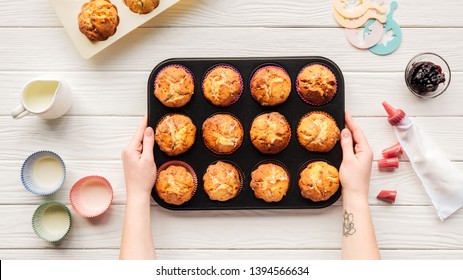 Cropped View Of Woman Holding Baking Tin With Cupcakes On Table With Baking Tools