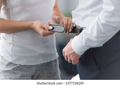 cropped view of woman holding belt near man standing in pants  - Shutterstock ID 1377136259
