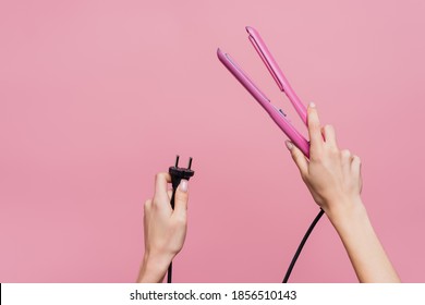 Cropped View Of Woman Holding Hair Straightener In Hands Isolated On Pink