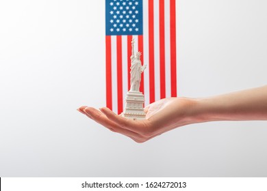 Cropped View Of Woman Holding Small Statue Of Liberty Near American Flag Isolated On White