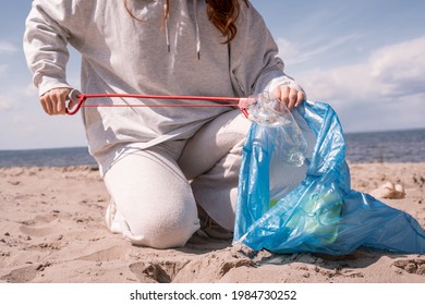 Cropped View Of Woman Holding Trash Bag And Picking Up Rubbish On Sand 