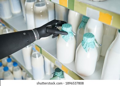 Cropped View Of The Woman Implant Hand Taking Bottle Of Milk From Shelf In Dairy Department Store. Customer Buying Milk While Filling And Stocking Shelves. Woman Choosing Food Products