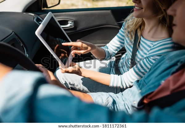 Cropped view of woman pointing at digital tablet\
while husband driving\
car