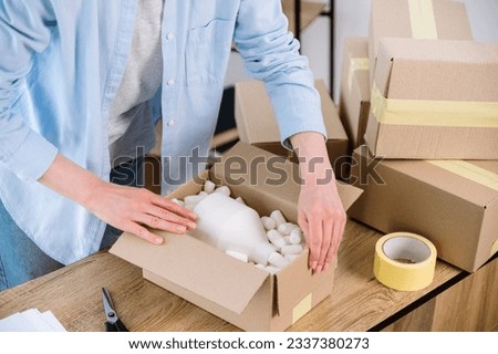 Cropped view of woman preparing parcel delivery for client. Entrepreneurs arranging fragile goods for shipping. Small warehouse for ecommerce. Advertising for shipment service, dropshipping business