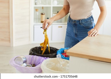 Cropped View Of Woman Putting Banana Peel In The Garbage Bin. Different Bins For Sorting Waste In The Kitchen