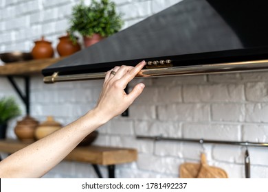Cropped view of woman select mode on cooking hood, standing near kitchen appliance in modern interior house with houseplant in flower pot on shelves - Shutterstock ID 1781492237