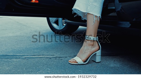 cropped view of woman in trendy footwear getting out\
of car