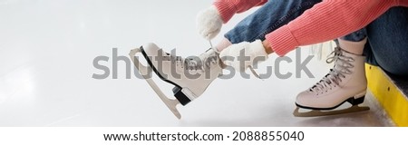 cropped view of woman tying shoe laces on ice skates, banner