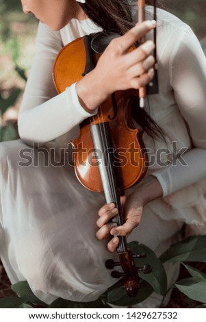 cropped view of woman in white swan costume holding violin