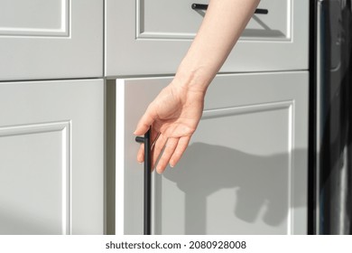 Cropped View Of Woman's Hand Opening White Wood Cupboard Door. Contemporary Kitchen Furniture Concept. New Luxury Apartment Details. Cabinet Usage