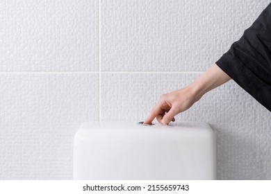 Cropped view of woman's hand pushing button and flushing toilet in bathroom. Everyday routine. Flush cleaning toilet. Contemporary facilities for people - Shutterstock ID 2155659743