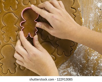 Cropped view of woman's hand using plastic gingerbread cookie cutter on worktop