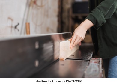 Cropped view of woodworker holding wooden plank near jointer machine - Shutterstock ID 2136216089