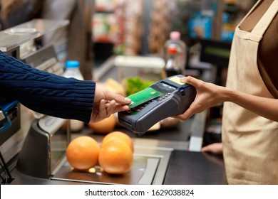 Cropped View Of Young Adult Man Holding Plastic Credit Card In Hand, Using Terminal And Paying For Shopping In Supermarket