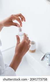 Cropped View Of Young African American Woman Holding Bottle With Serum In Bathroom