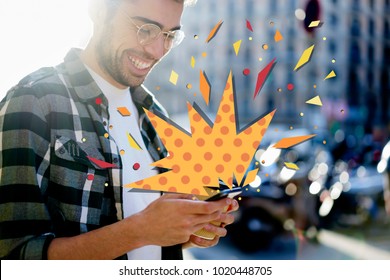 Cropped View Young Hipster Guy Receives Discounts Notification On Smartphone With Surprise Infographics Elements Effect. Cheerful Male Reading Text Message On Cellular While Standing On City Street