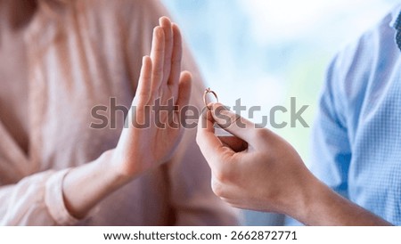 Cropped view of young lady refusing marriage proposal, gesturing NO to man with engagement ring, indoors