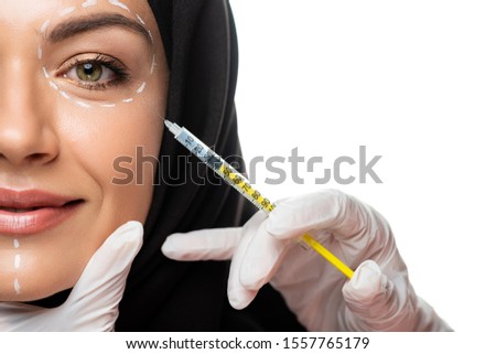 cropped view of young Muslim woman in hijab with marks on face having beauty injection isolated on white