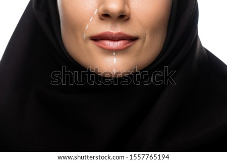 cropped view of young Muslim woman in hijab having marks on face for plastic surgery isolated on white