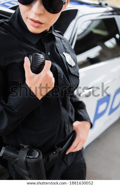 cropped view of young policewoman\
talking on radio set on blurred background\
outdoors