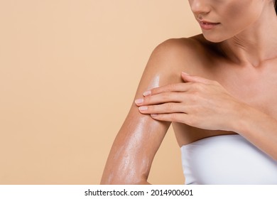 cropped view of young woman applying sunblock isolated on beige