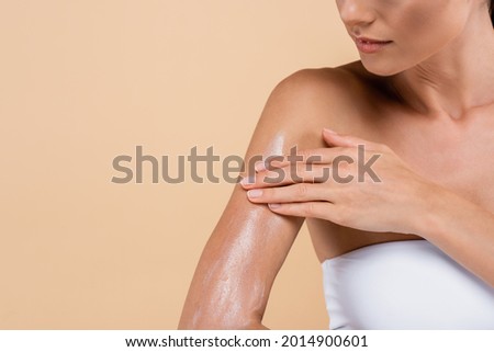 cropped view of young woman applying sunblock isolated on beige
