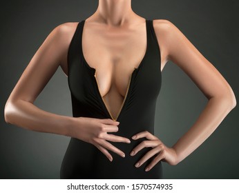 Cropped view of young woman in black dress showing cleavage, studio shot