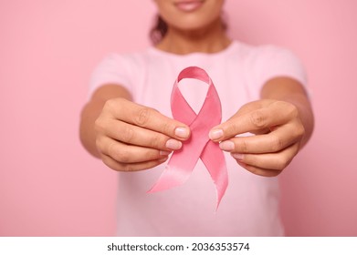 Cropped view of a young woman in pink t-shirt holding a pink satin ribbon isolated on colored background with copy space. International Breast Cancer awareness Day, Breast cancer support concept. - Shutterstock ID 2036353574