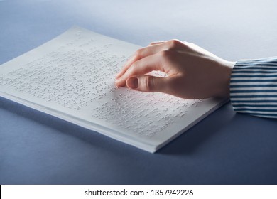 cropped view of young woman reading braille text with hand on blue - Powered by Shutterstock