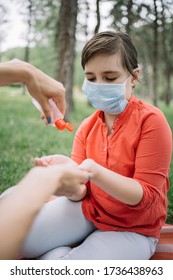 Cropped Woman Putting Hand Sanitizer On Kid's Hands Outdoor. Woman's Hands Holding Disinfectant While Sanitizing Little Girl's Hands In Park.