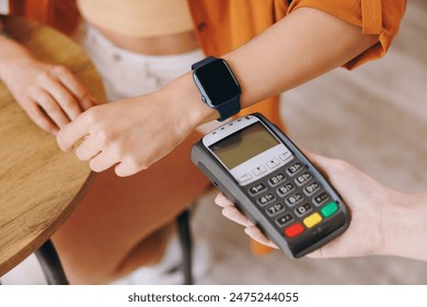 Cropped woman wear shirt hold bank payment terminal to process acquire smart watch pay bill sitting alone at table in coffee shop cafe relax rest at restaurant Freelance mobile office business concept - Powered by Shutterstock