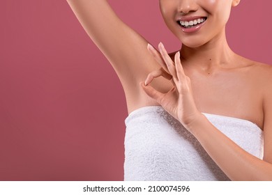 Cropped of young asian woman wrapped in towel lifting hand up, showing clean and hygienic armpits or underarms, giving okay sign, purple background, copy space. Smooth armpit, underarm odor