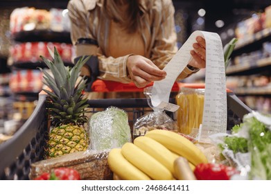 Cropped young customer woman wear casual clothes read check bill shopping at supermaket store grocery shop buying with trolley cart choose products in hypermarket. Purchasing food gastronomy concept - Powered by Shutterstock