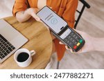 Cropped young woman hold bank payment terminal to process acquire mobile cell phone pay bill sits alone at table in coffee shop cafe relax rest at restaurant indoor. Freelance office business concept