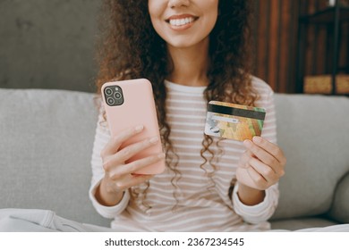 Cropped yyoung happy woman wear casual clothes sits on grey sofa couch using mobile cell phone credit bank card shopping online stay at home hotel flat rest relax spend free time in living room indoor - Shutterstock ID 2367234545