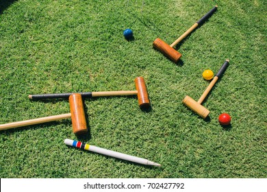 A croquet set lies on green grass.