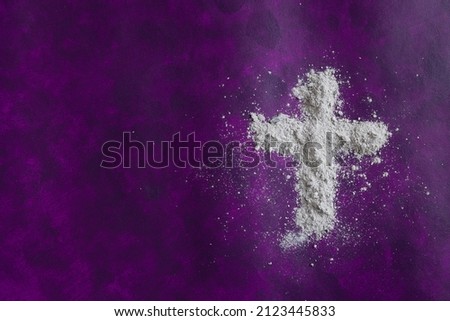Cross of ashes on a dark purple background with copy space