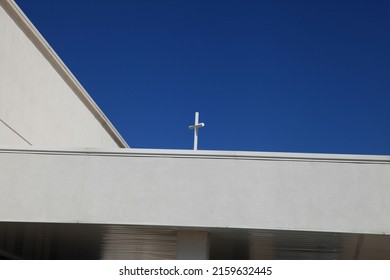 Cross Behind The Parapet Wall With The Blue Clear Sky.