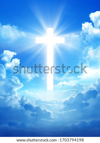 Cross in the cloudy sky with light rays