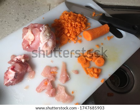 Cross contamination of food, raw chicken and carrots on the same chopping board