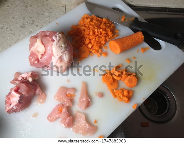 Cross contamination of food, raw chicken and\
carrots on the same chopping\
board