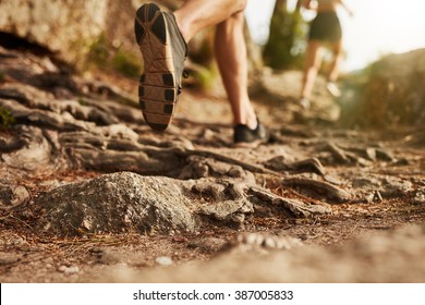 Cross country running. Closeup of male feet run through rocky terrain. Focus on shoes.