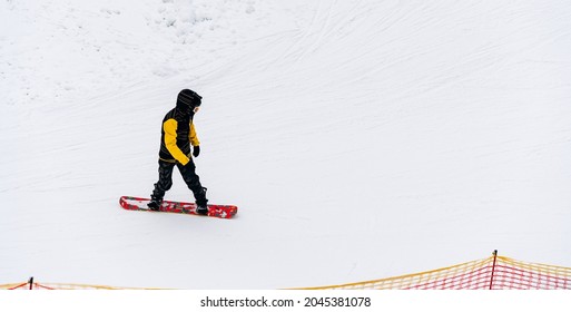 Cross country snowboarding in beautiful winter landscape. Male snowboarder is walking at the hill. Touring in mountains. Cloudy weather. Sport concept 