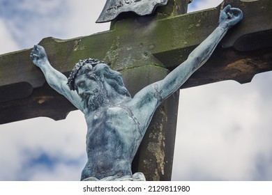 Cross with a crucified figure of Jesus Christ. Close up of Jesus Christ against the background of blue sky. Old, stone cross in the summer.