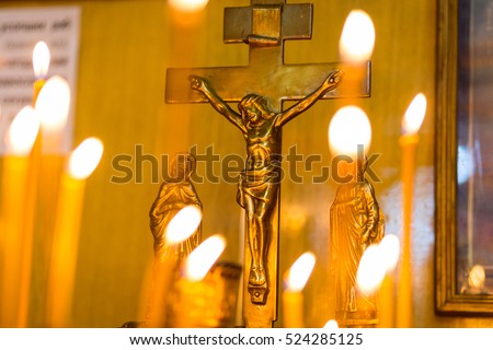 Cross with a crucifix on a background of burning candles